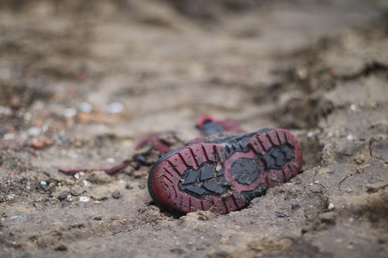 A child's shoe covered by mud