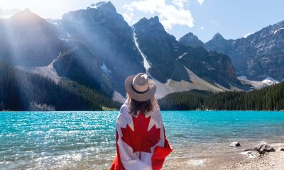 Person With A Canadian Flag Around Her Standing Near Lake