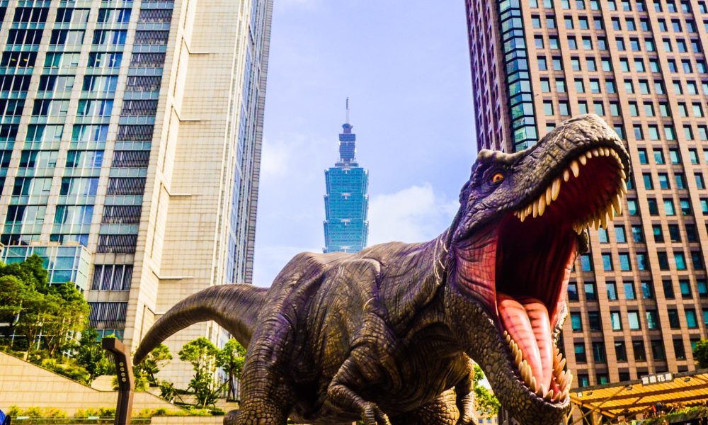 a dinosaur outside city buildings