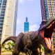 a dinosaur outside city buildings