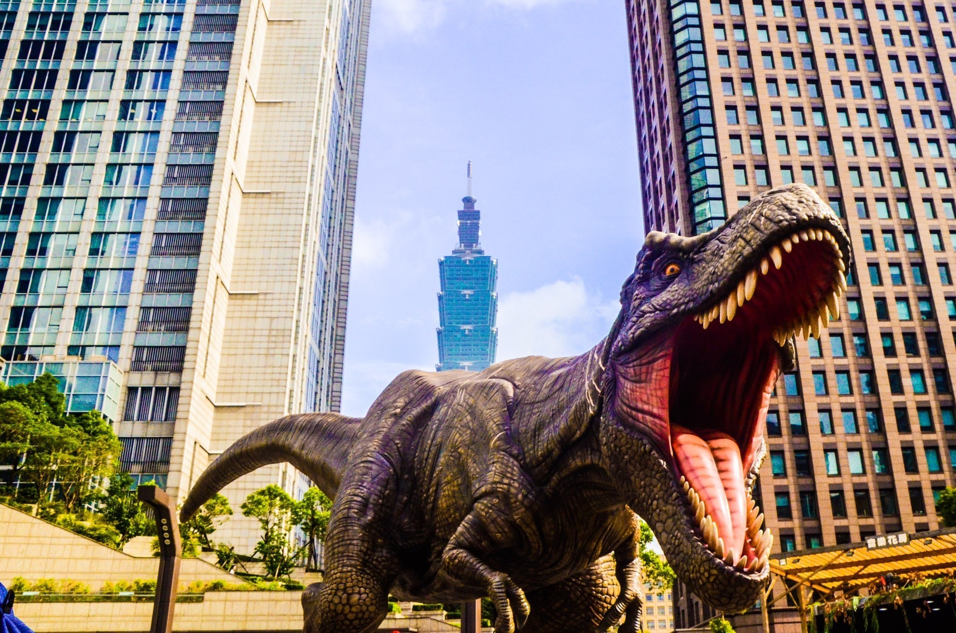 a dinosaur outside city buildings