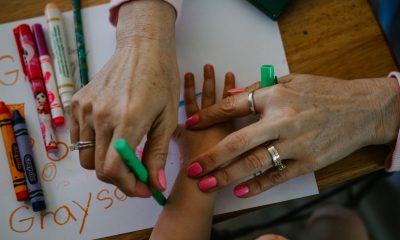 parent's hand helping child's hand in coloring