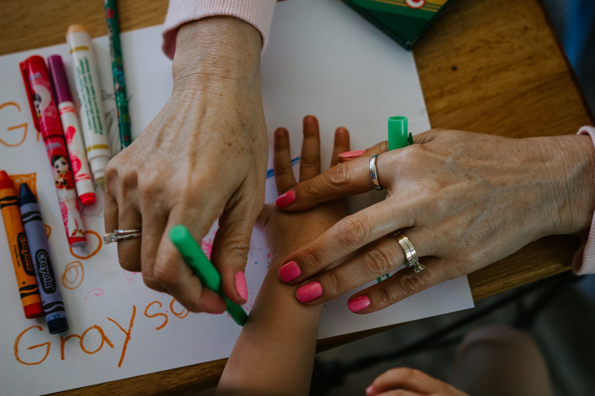 parent's hand helping child's hand in coloring