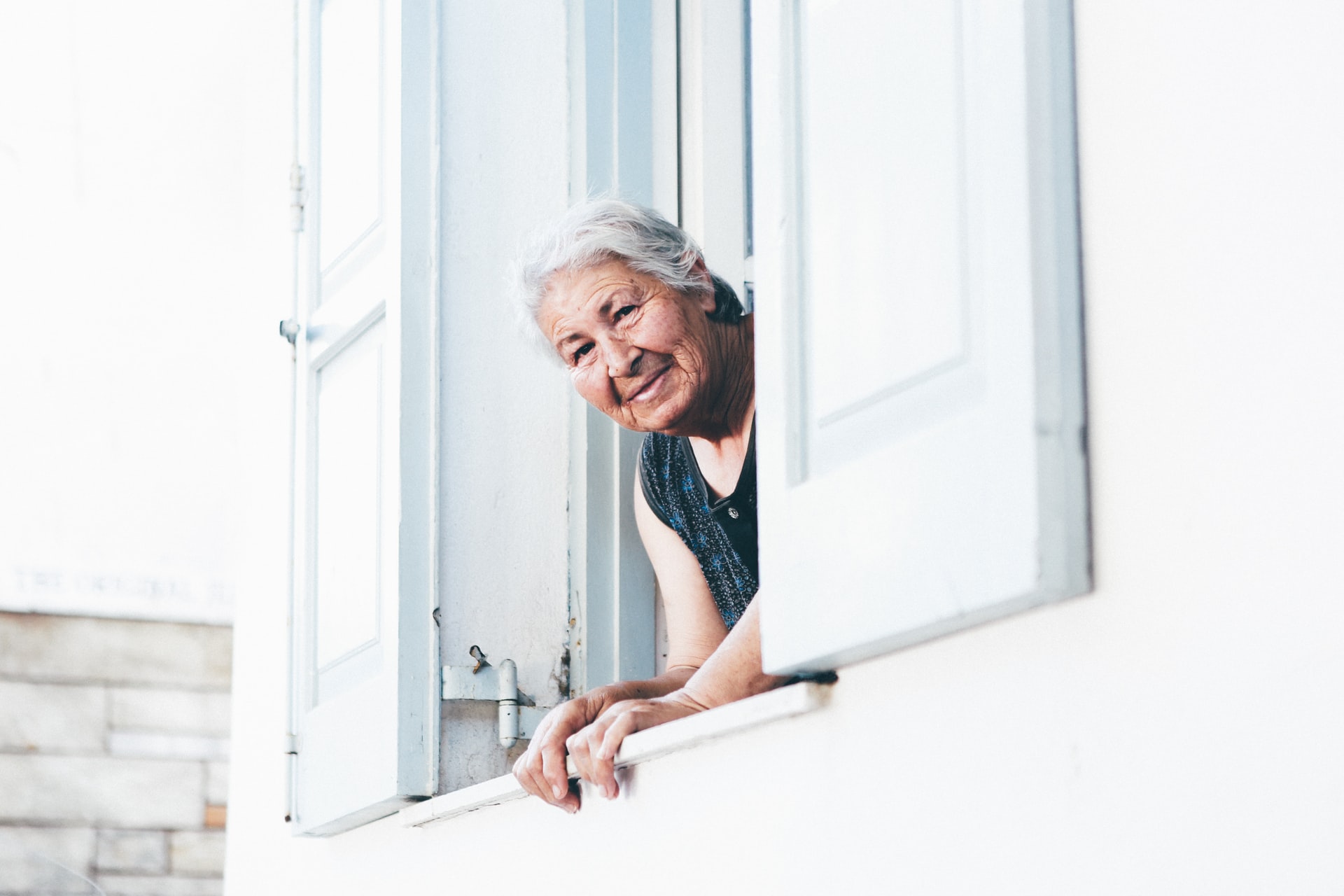 An old lady peeking out from a white window