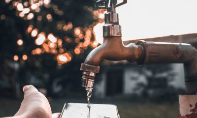 person holding phone under tap water