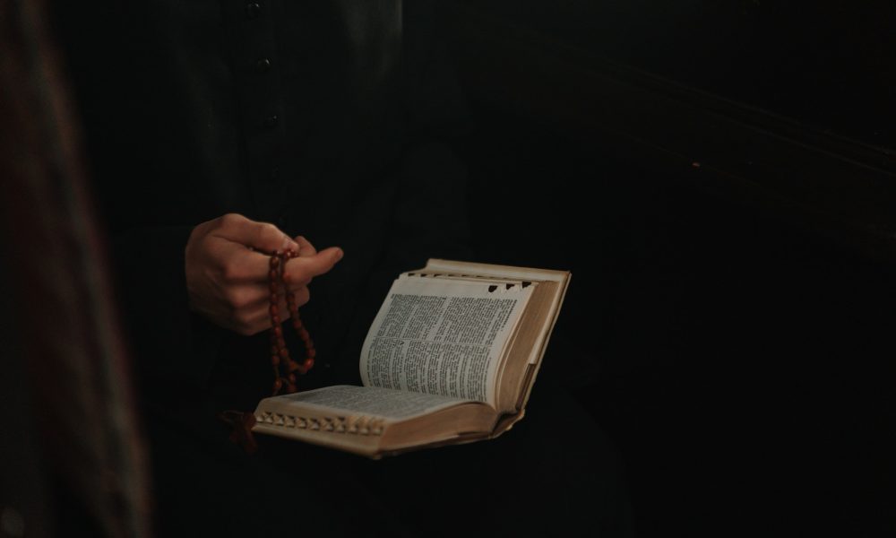 Person holding a bible and rosary