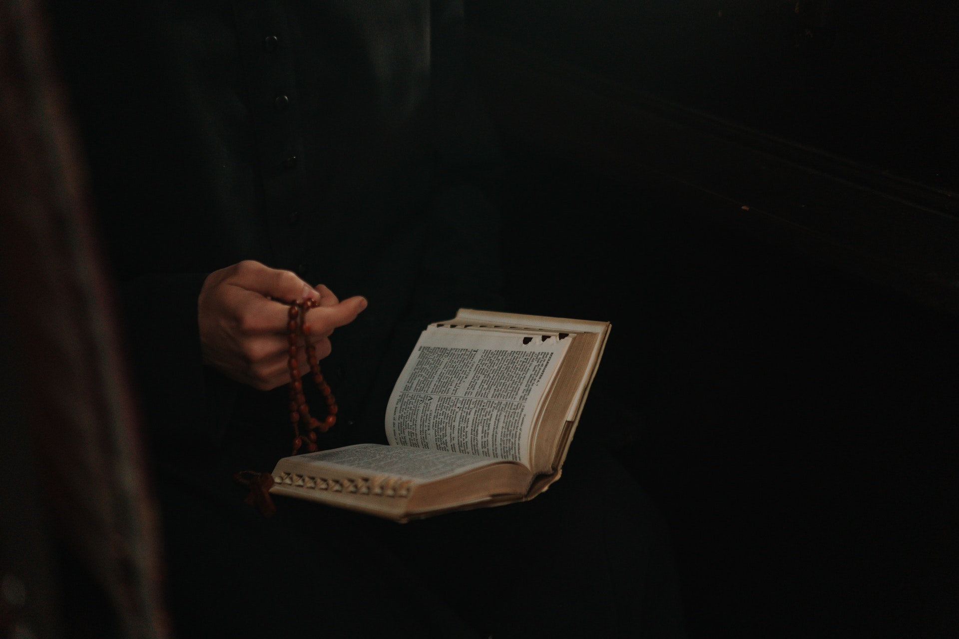 Person holding a bible and rosary