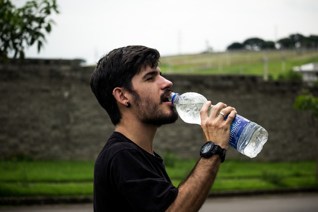 man drinking from plastic bottle