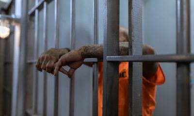 tattooed man wearing orange shirt inside a jail