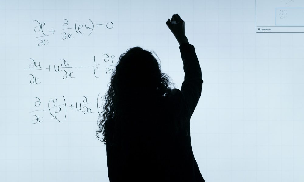 woman solving math equation on board