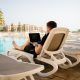 man working on laptop in front of pool