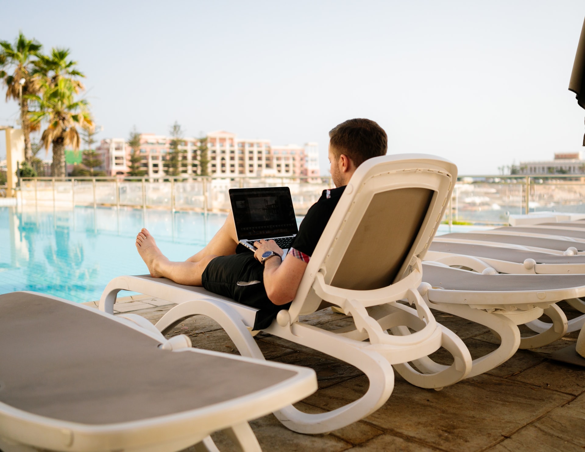 man working on laptop in front of pool
