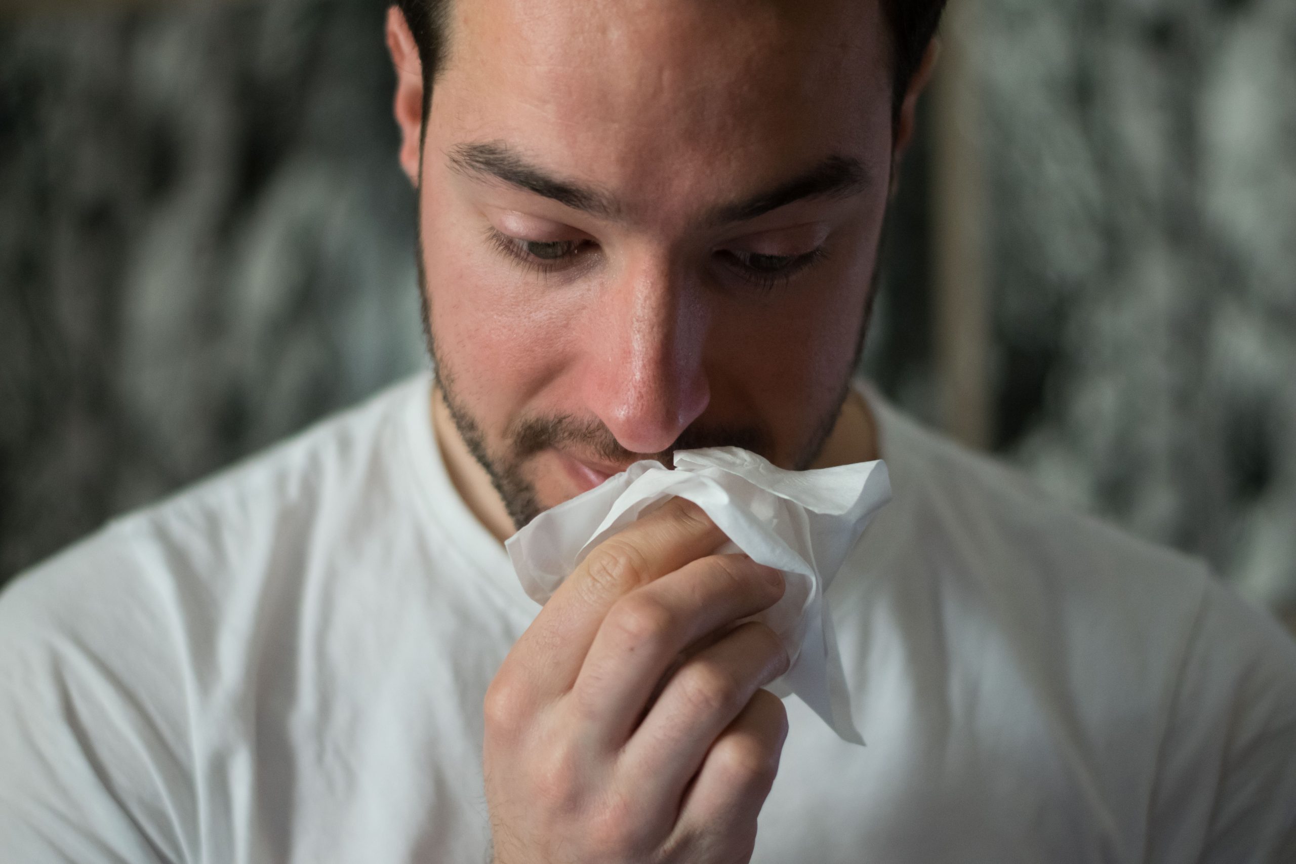 Man wiping his nose with tissue paper