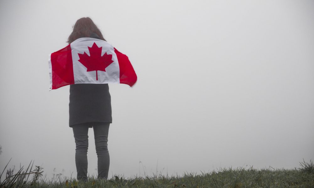 Woman with Canadian flag standing on grass field