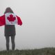 Woman with Canadian flag standing on grass field