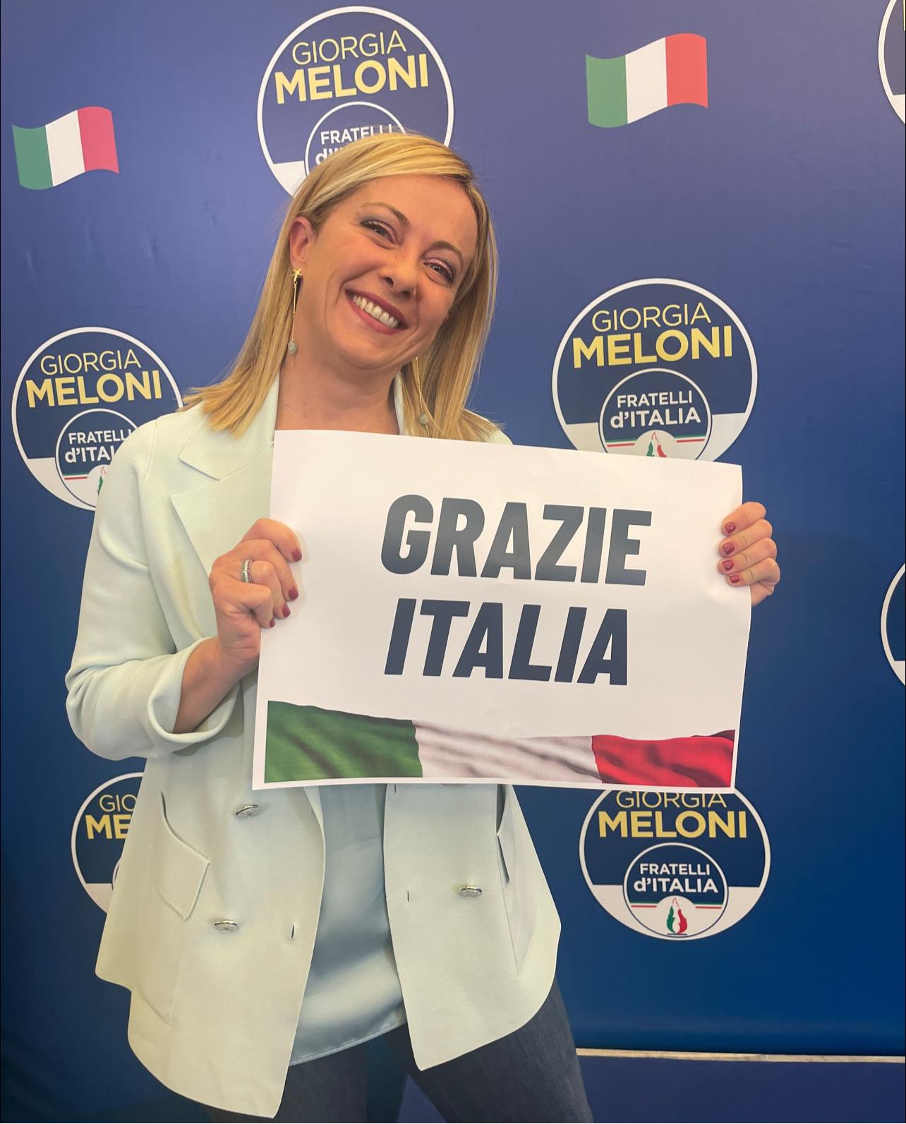 Giorgia Meloni holding paperr with 'Grazie Italia'