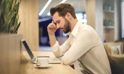 Man With Hand on Temple Looking at Laptop