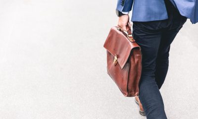 Person walking holding a brown leather bag
