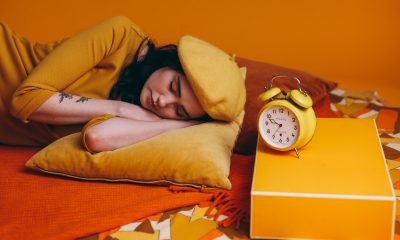 Woman Lying on Bed Beside A Yellow Analog Alarm Clock