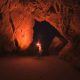 Person Standing and Holding Lamp Inside Cave