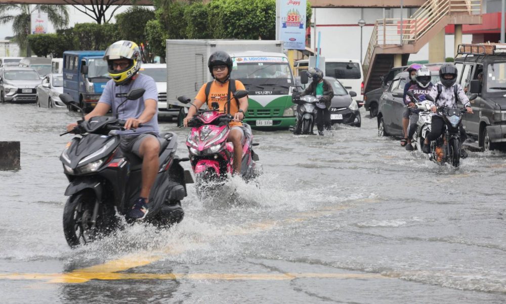 motorcycle riders pass through flooded road