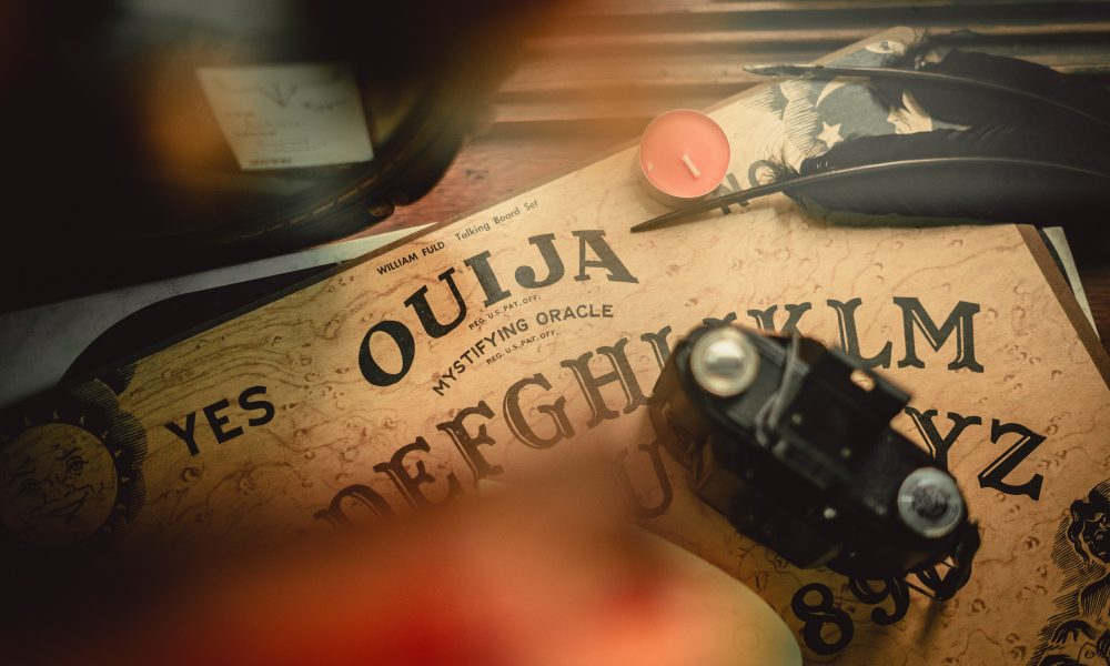 Antique ouija board with vintage camera and feathers