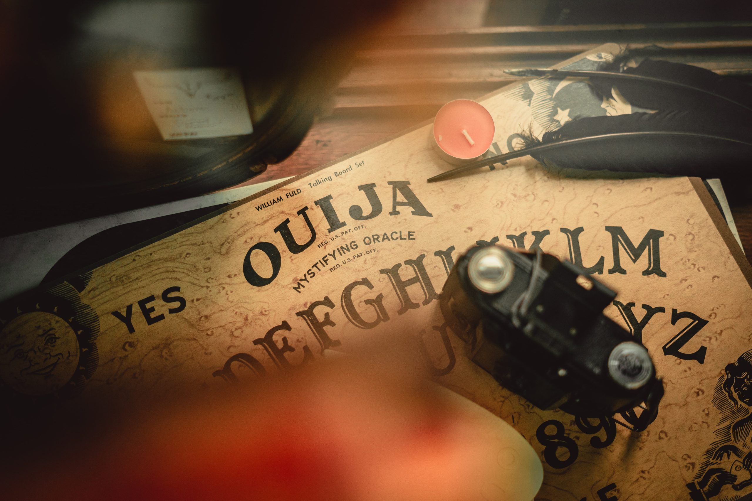 Antique ouija board with vintage camera and feathers