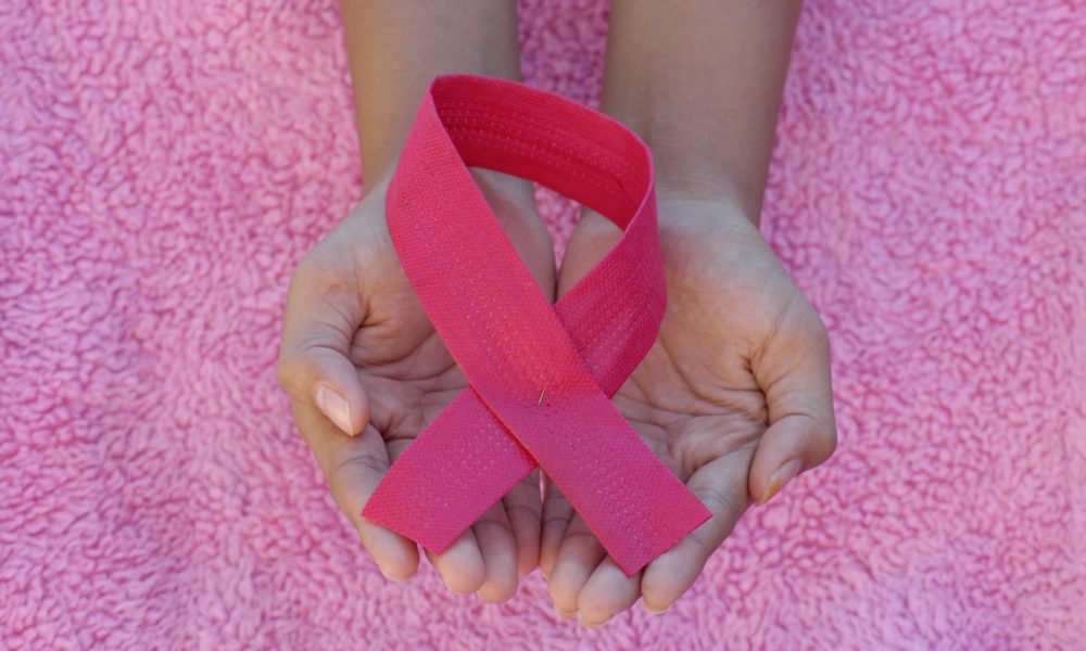 Hand holding a pink ribbon