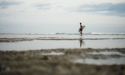 Man Holding His Surfboard While Walking on the Beach