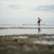 Man Holding His Surfboard While Walking on the Beach