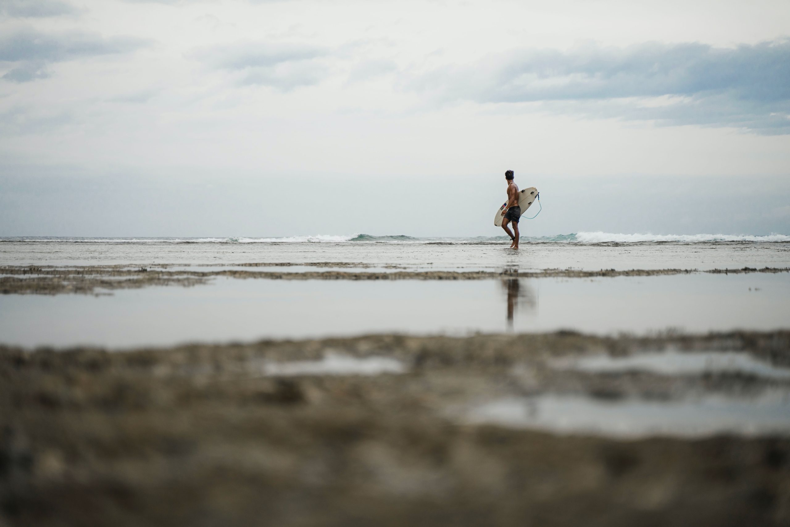 Man Holding His Surfboard While Walking on the Beach