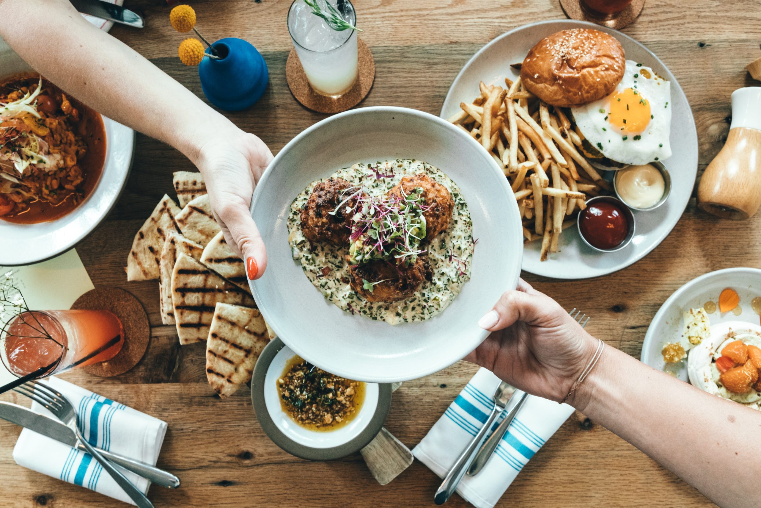 Two persons holding white plate with food