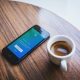White Ceramic Teacup Beside Black Iphone 5 on Brown Wooden Table