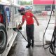 gasoline attendant fills up the fuel tank of a jeepney
