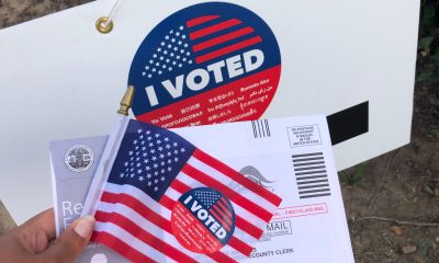 person holding mail and i voted usa flag