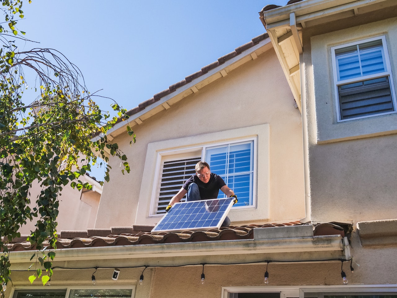 man applying solar panel on roof