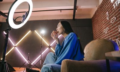 A Woman Recording Herself Eating Pizza with a Smartphone