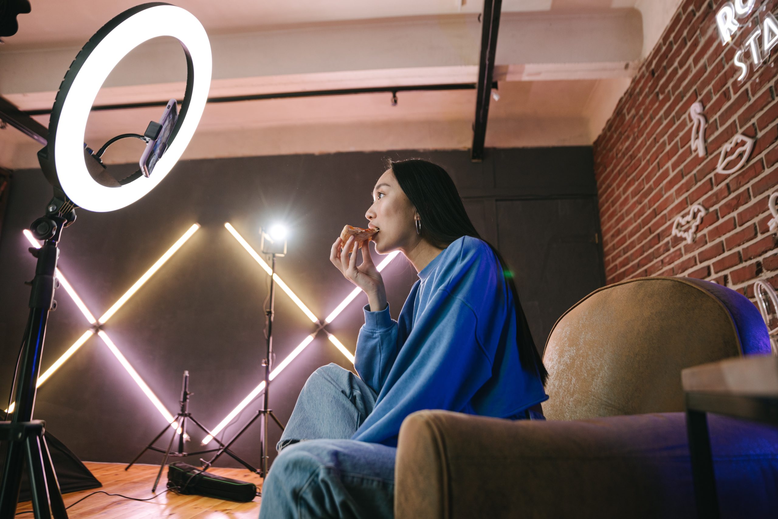 A Woman Recording Herself Eating Pizza with a Smartphone