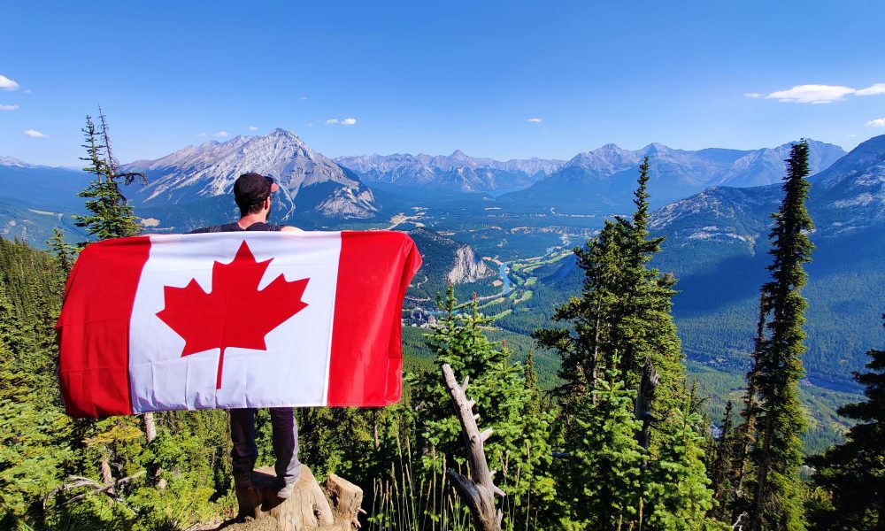 A hiker holding a Canada flag over Banff.