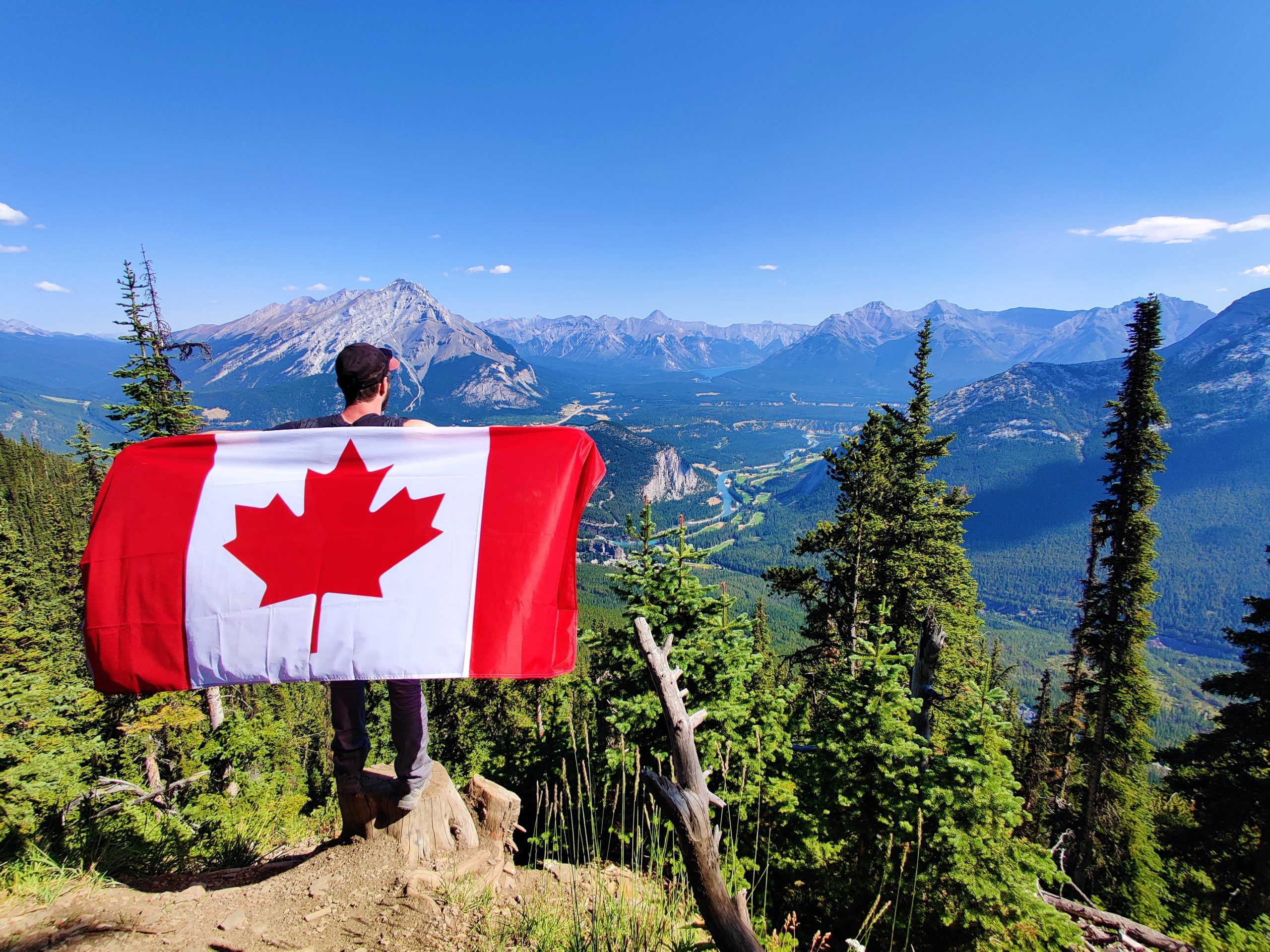 A hiker holding a Canada flag over Banff.