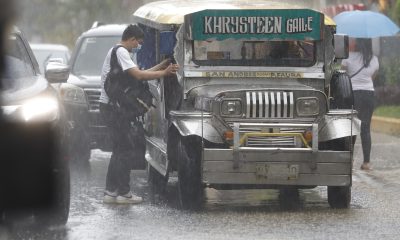 A man rushes to get on a public utility jeepney during a heavy downpour