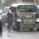 A man rushes to get on a public utility jeepney during a heavy downpour
