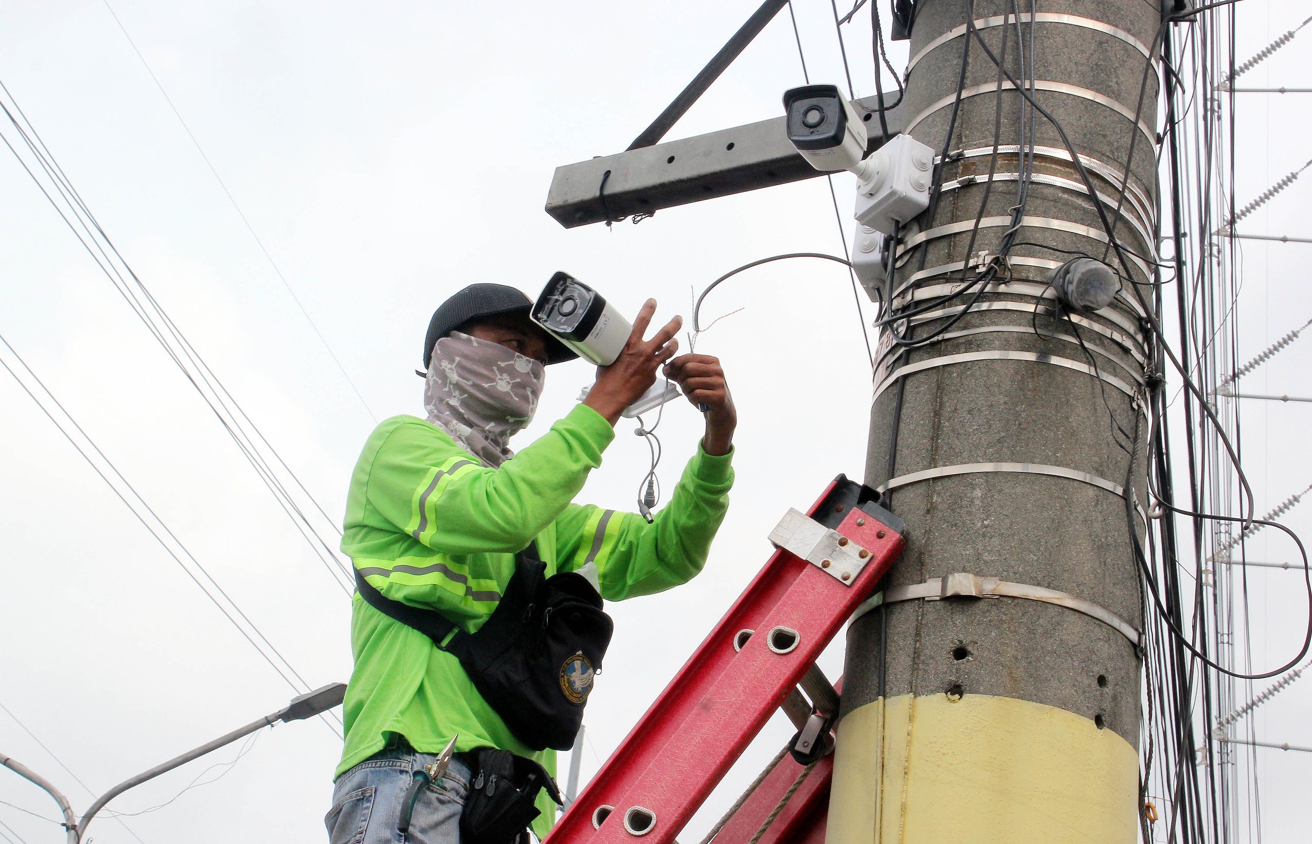 A worker installs closed-circuit television cameras on a concrete post