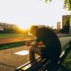 Man Sitting on Bench Near Track Field While Sun Is Setting