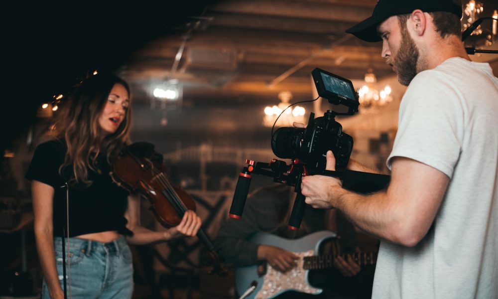 Man Taking a Video of a Woman Carrying a Violin