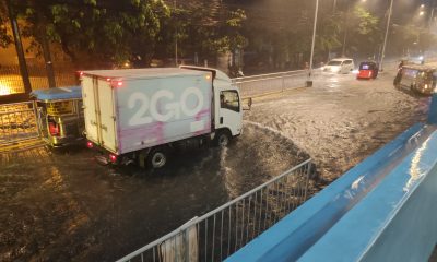 Motorists slowly pass the flooded portion of the Natividad Almeda-Lopez Street