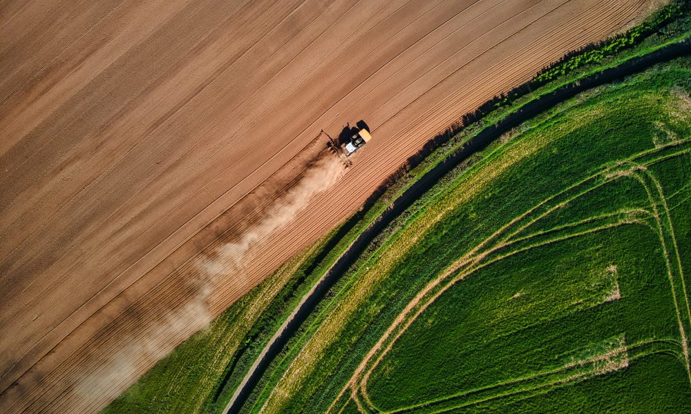 Farmers prepping the once lush green fields on a dusty Spring afternoon in Devon