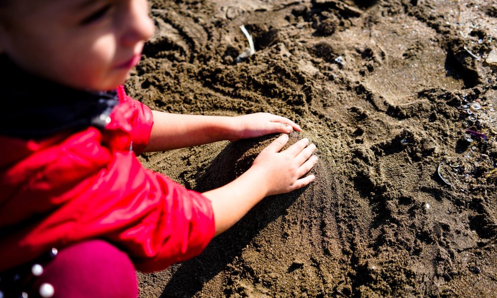 Kid playing on wet sandy beach