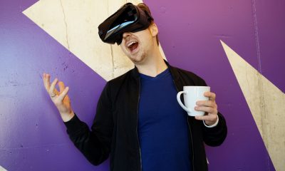 Man Wearing Black Virtual Reality Headset while Holding White Mug