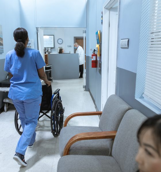 Nurse Pushing a Wheelchair on Hospital Hallway